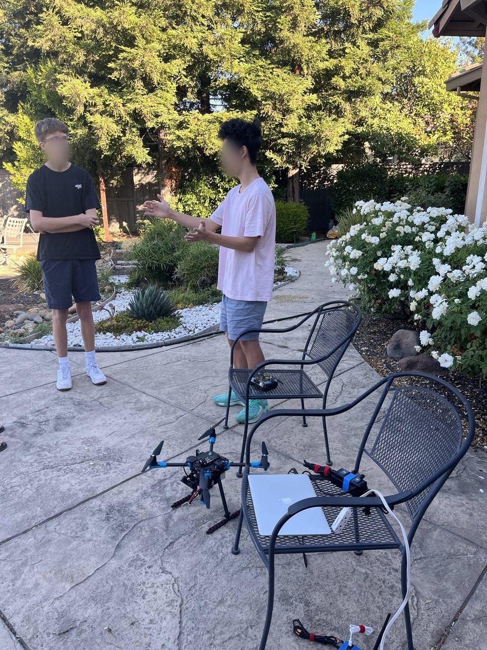 Students discussing drone technology beside a drone and laptop during an outdoor gathering